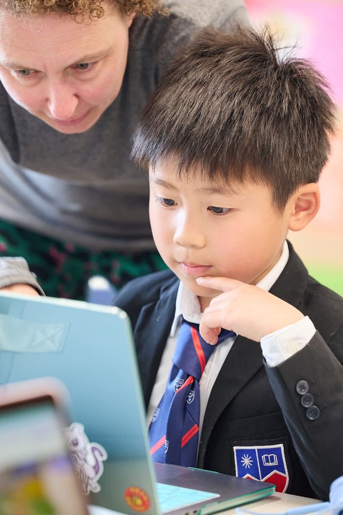 A Primary School student using a laptop with guidance from a teacher at La Garenne.