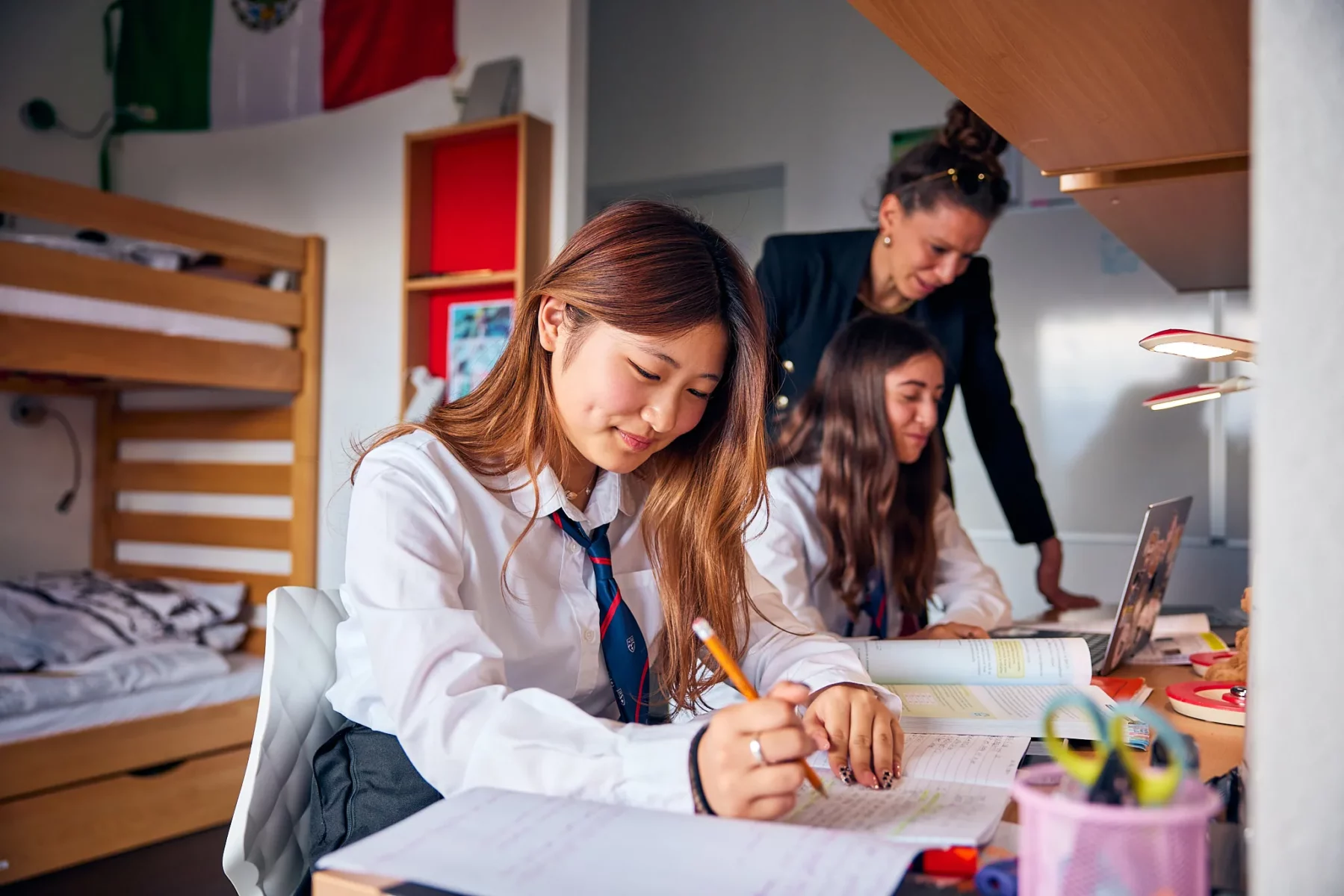 A boarding student doing homework in her room with a houseparent helping