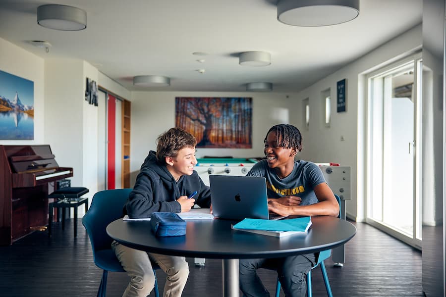 Two Beau Site boarders working together on a computer in the student lounge at La Garenne’s Chalet Beau Site.