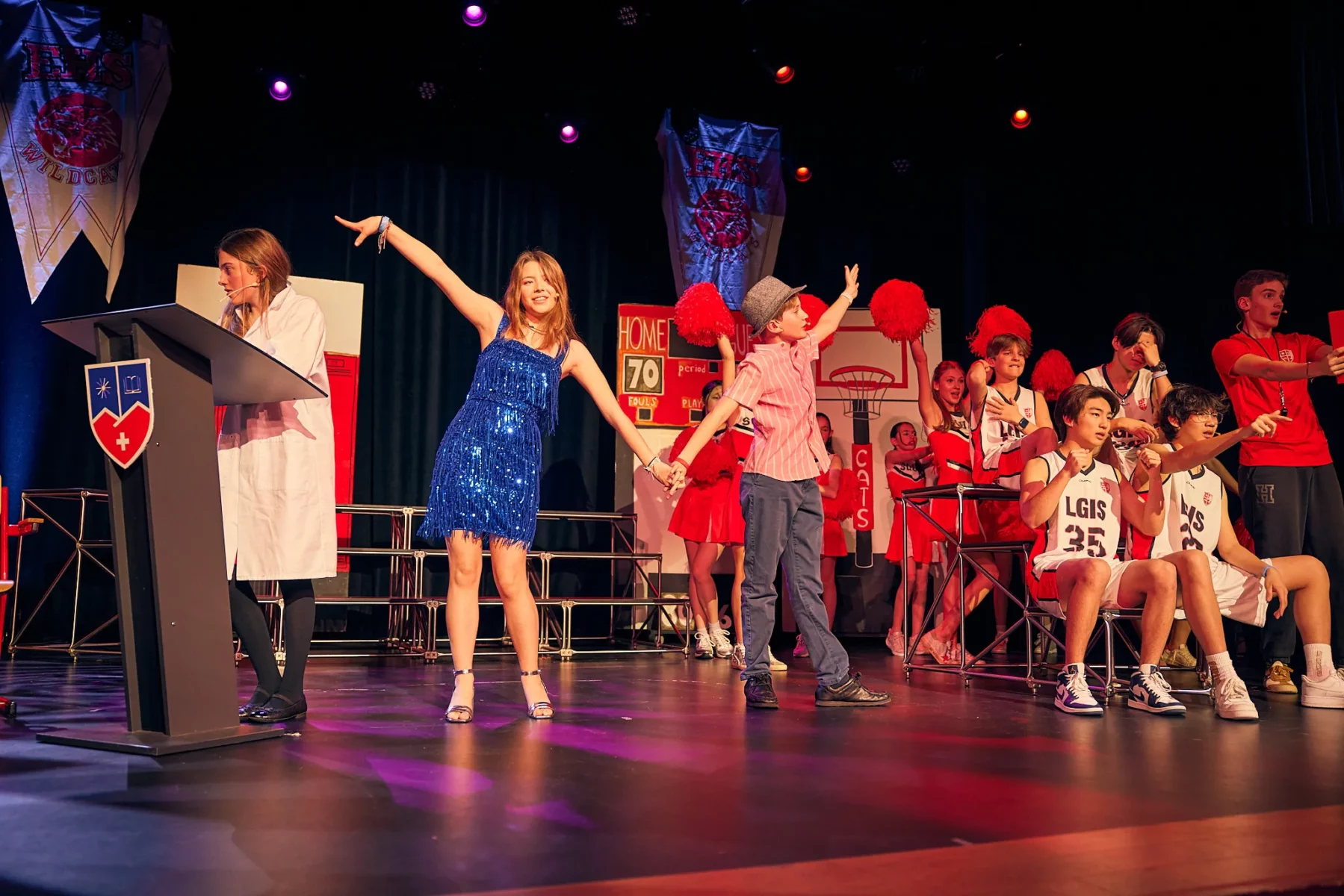 Students performing a school musical on stage in colourful costumes